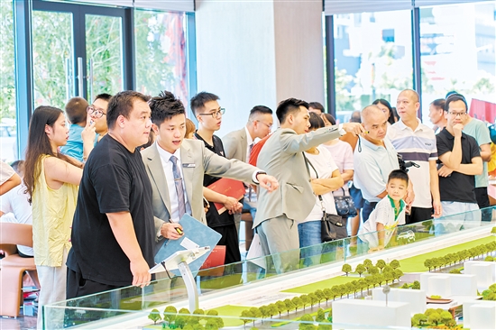 在駿景灣·品悅，銷(xiāo)售人員忙著為客戶(hù)介紹樓盤(pán)情況。