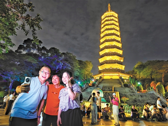 成功登頂?shù)氖忻衲贸鍪謾C(jī)與龍光塔合影。