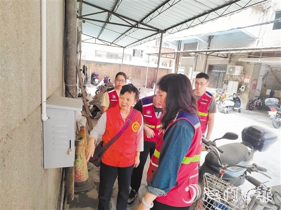 退休黨員干部鄧玉歡與網(wǎng)格員一起就充電樁選址開展調(diào)研。