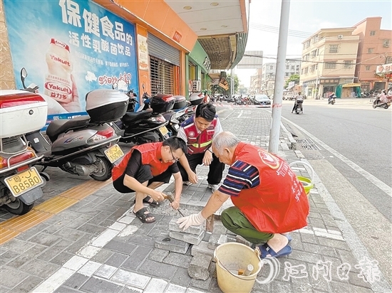 網(wǎng)格員和志愿者一同修復(fù)路面。