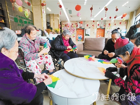 老人們圍坐在桌前，專注地制作小風(fēng)車。