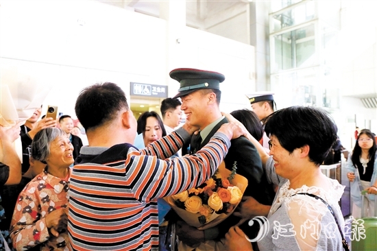 身著軍裝的返鄉(xiāng)退役士兵逐一出站，迎接他們的是鮮花與擁抱。