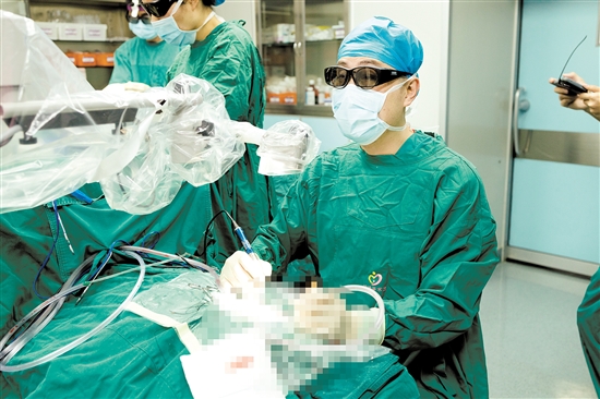 術中，醫(yī)生查看顯示屏，為患者植入人工耳蝸。