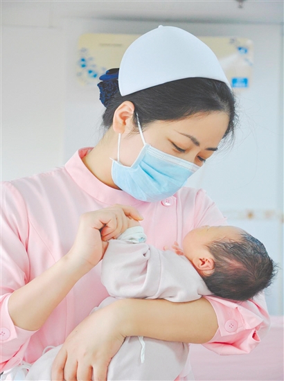 這是一雙托起生命的手。江門市中心醫(yī)院愛嬰?yún)^(qū)主管護(hù)師湯玲玲正在安撫哭鬧的寶寶。她一手環(huán)住襁褓，一手牽起寶寶的小手，動(dòng)作舒緩而溫柔。在這里，生命的啼哭與溫柔的守護(hù)相遇，匯聚成世間至暖的力量。（林錦棠