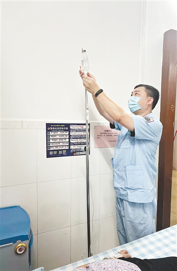 吳益浩核對藥液、為患者調(diào)整輸液流速。