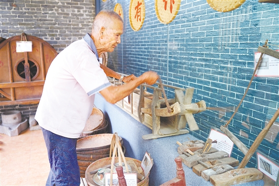 新華村打造農(nóng)耕文化展館，留住鄉(xiāng)村記憶。圖為村中老人向記者介紹農(nóng)具。