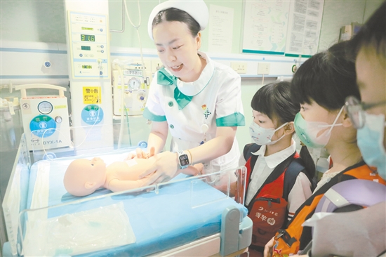 醫(yī)護人員為小記者演示新生兒輻射保暖臺的用途。