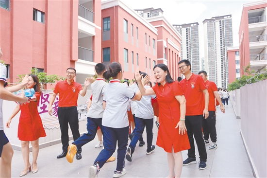 蓬江區(qū)紫茶中學的領導和老師們與考生們擊掌，為他們加油、鼓勁。