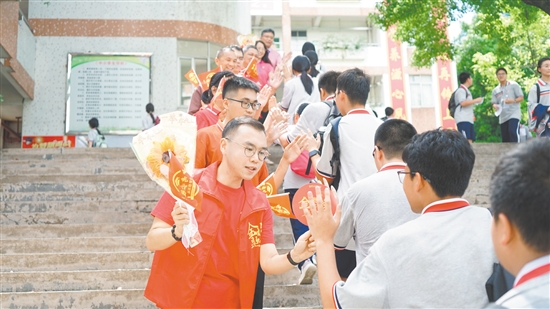 在景賢學?？键c，老師們手持向日葵和小紅旗為考生加油。