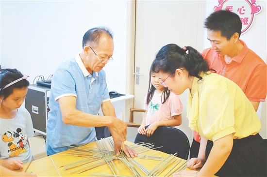 孩子和家長在手藝人的指導下學習編織小竹筐。