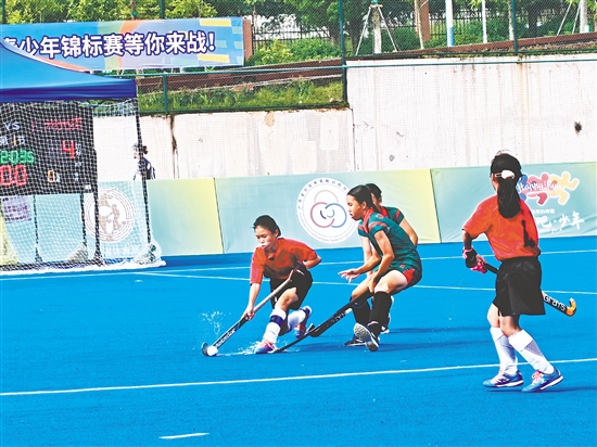 共和鎮(zhèn)中心小學(xué)女子曲棍球隊隊員（紅色隊服）在比賽中頑強拼搏。