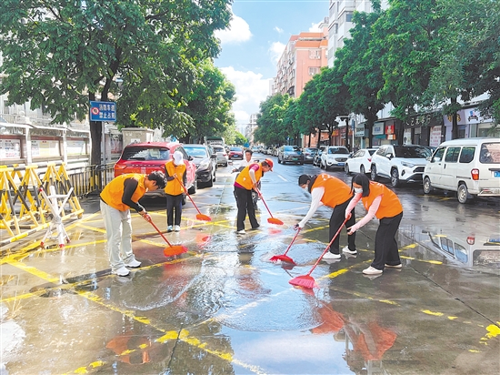 廣東江門中醫(yī)藥職業(yè)學院大學生志愿者合力清掃街道積水。