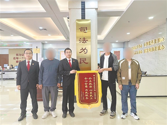 工人領(lǐng)到工資后,為法官團(tuán)隊(duì)送來(lái)錦旗致謝。